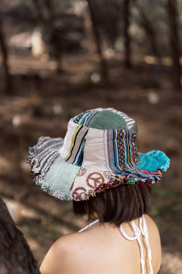 Nomad's Nirvana Hat with cream base, multicolored striped panels, geometric patterns, frayed brim edges, shown on model.