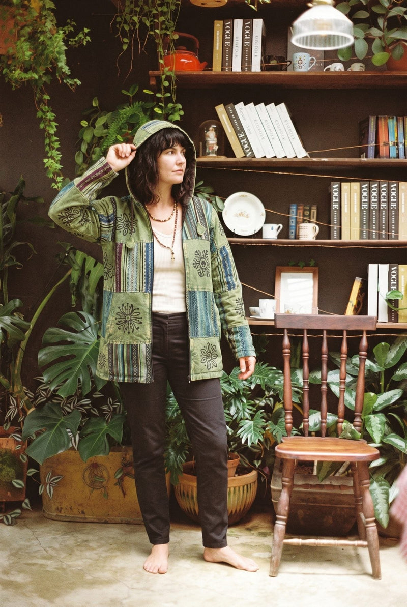 Green Horizon Patchwork Jacket worn open with the hood up, arm raised, green patchwork panels in view.
