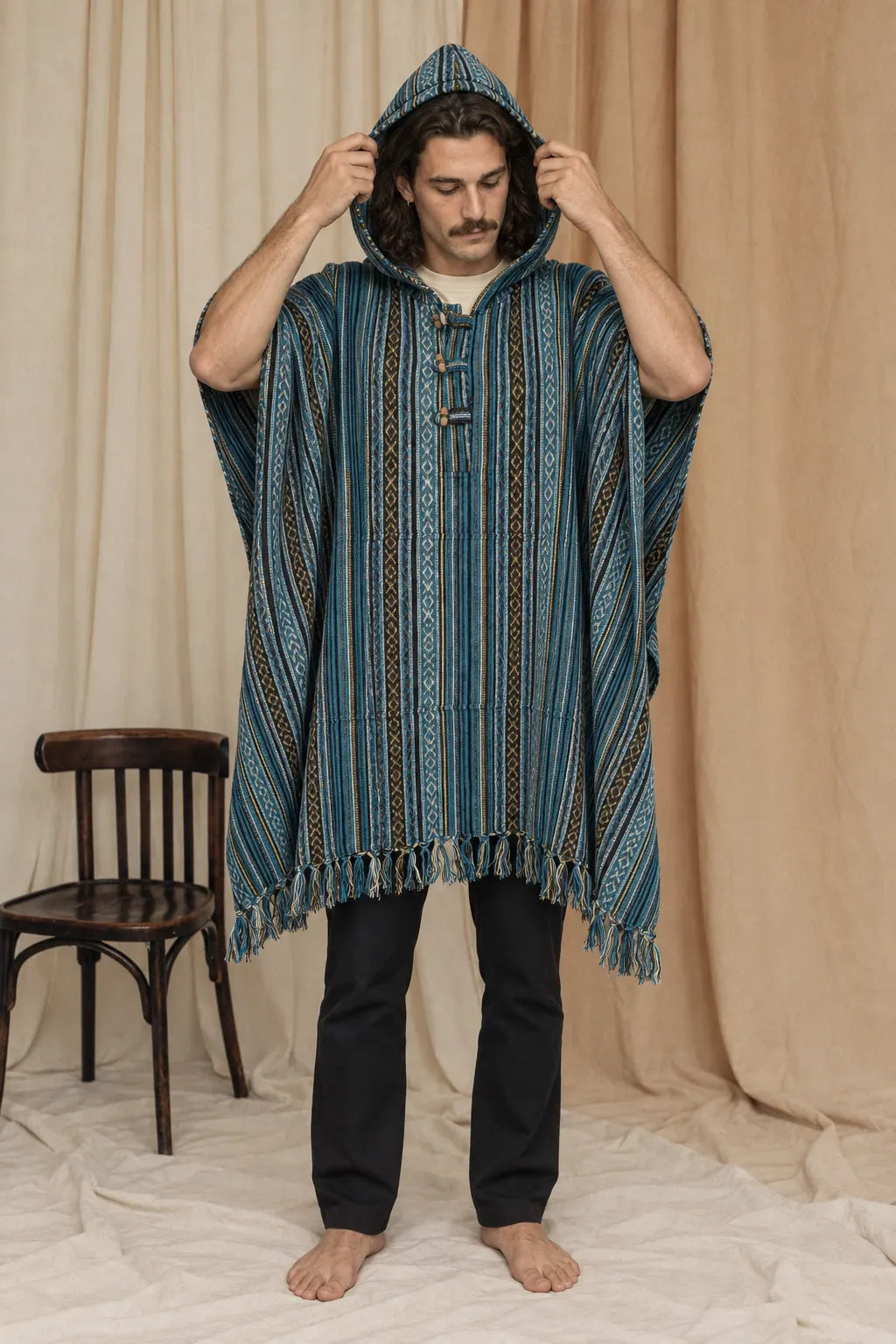 Tidewater Gheri Poncho, teal, blue and black stripe, worn with the hood up by a model in the calico studio