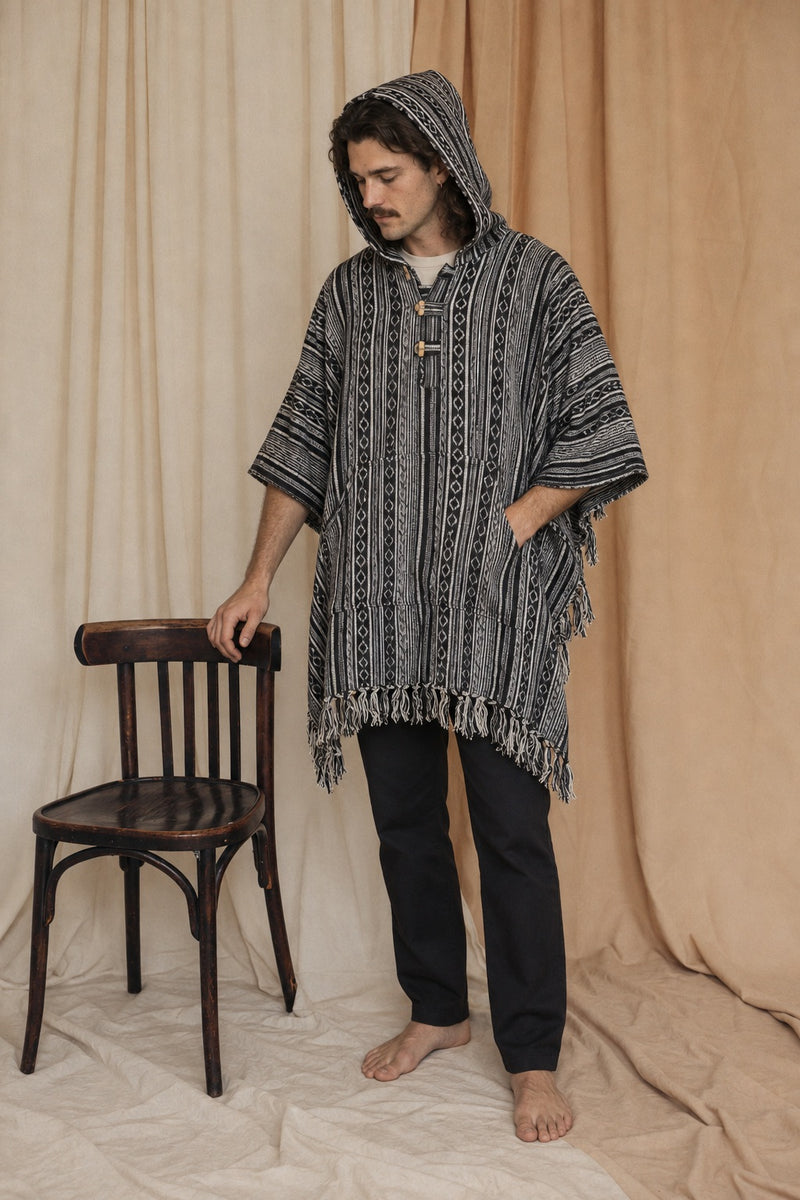 Reed wearing the Handmade Black Nepalese Poncho, hood up, studio
