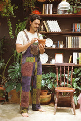 Close view of the Duskwood Overalls bib pocket and adjustable straps as a man tends a terracotta pot of seedlings