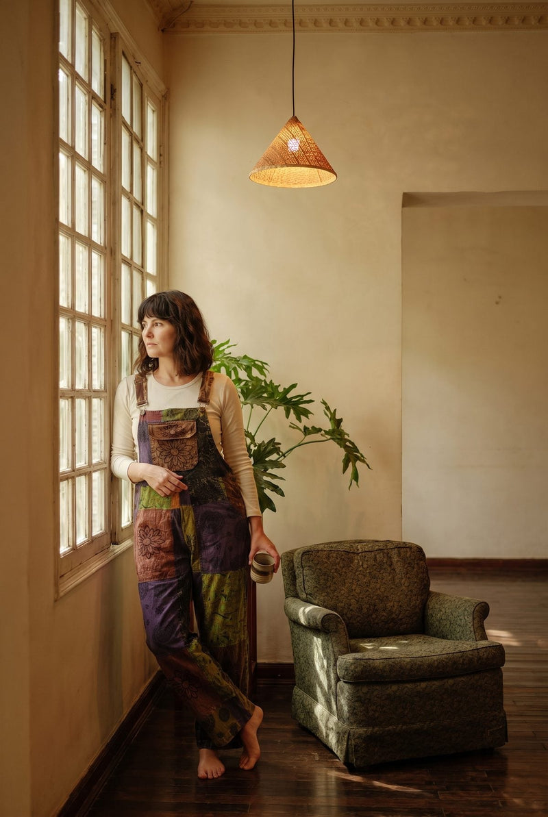 Duskwood Overalls in a wider room shot, purple, olive and rust patchwork with a floral-stamped chest pocket.