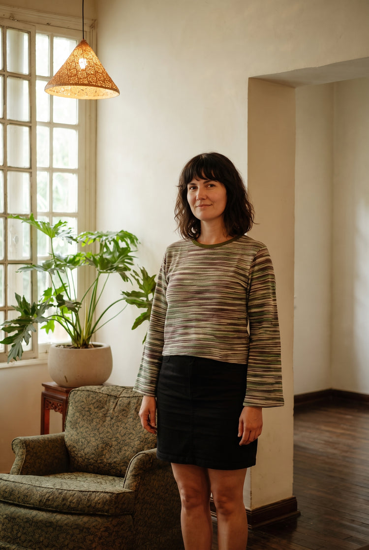 Model wearing the Lichen Knit Top in Moss: space-dyed knit with flared bell cuffs and olive neckband.