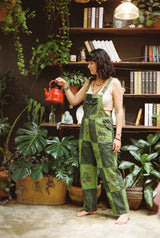 Woman lifting a red kettle in the Sungrove Overalls, green checkerboard patchwork dungarees with block-printed mushrooms and sunbursts