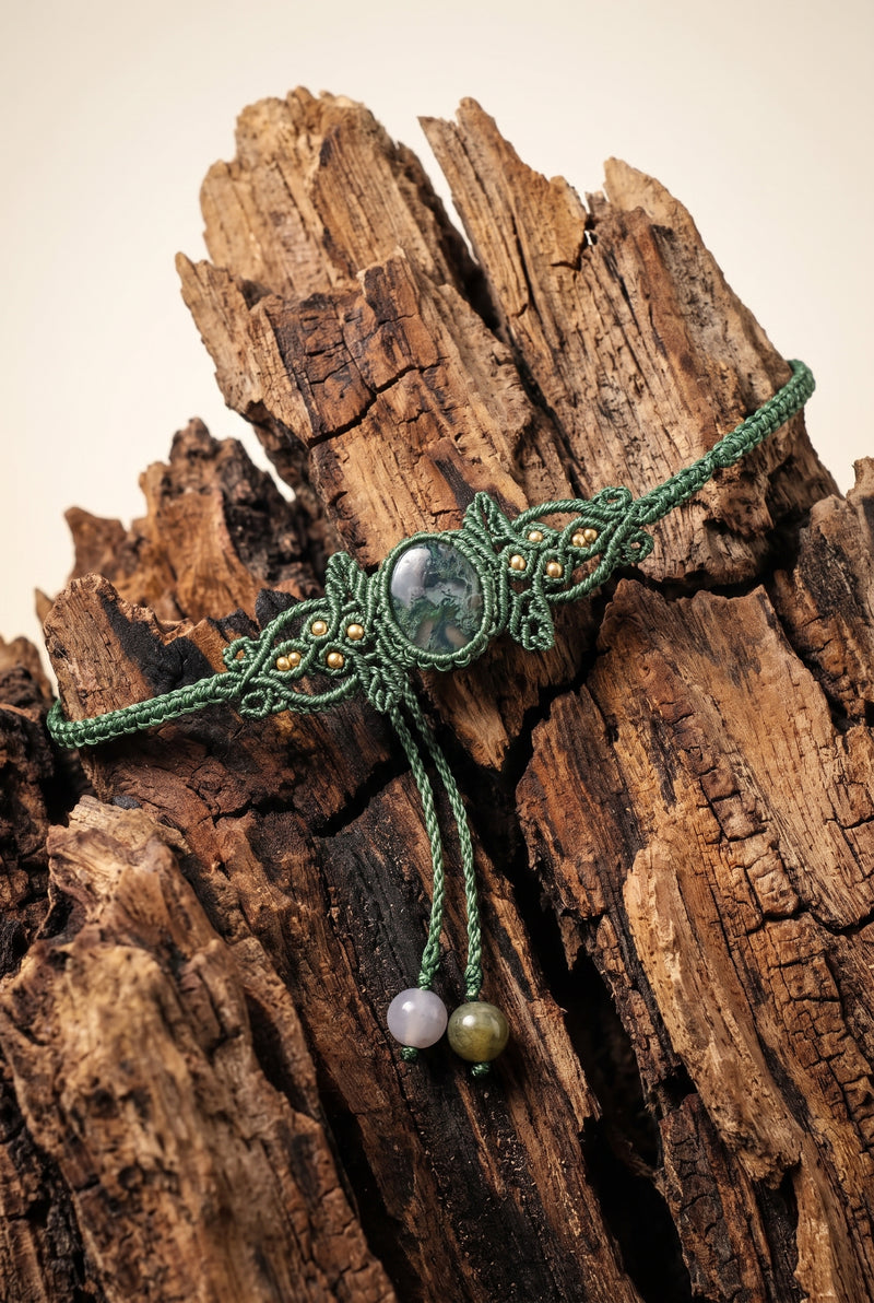 Woven Moss Agate Bracelet with pale moss agate stone in lighter green macramé cord and brass beads, draped over weathered driftwood.