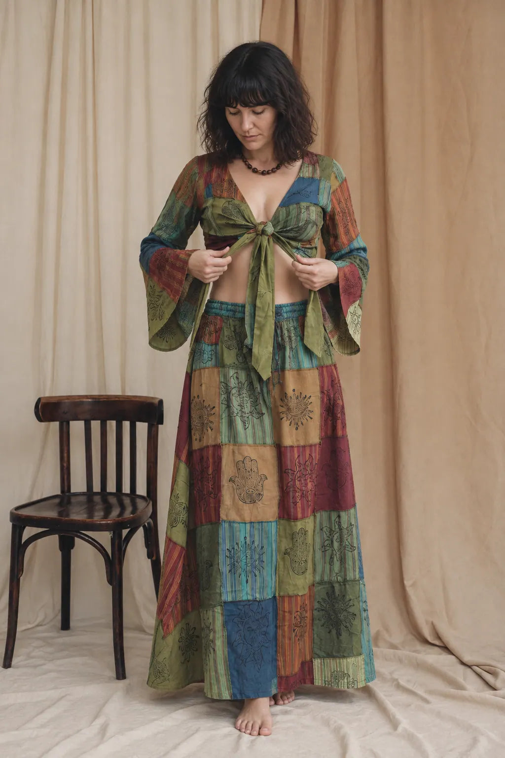 Fern and Fire Set, deep greens, ambers and reds, worn by a model standing in the calico studio, holding the tie of the top