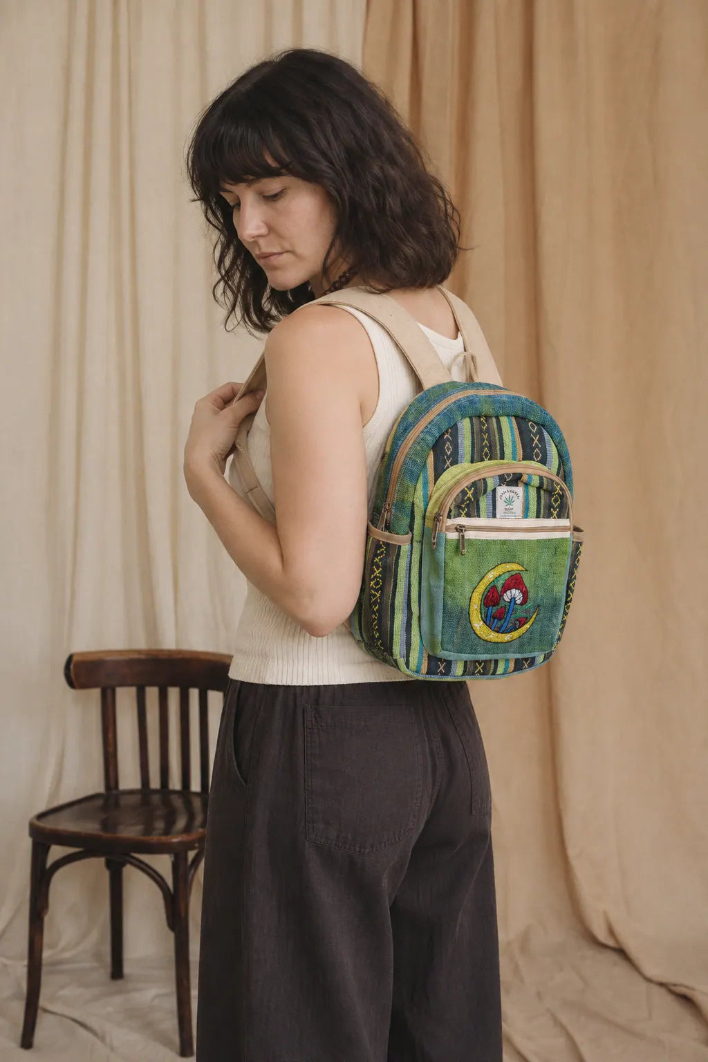 Moonshroom Gheri Backpack, green stripe, mushroom patch, worn over one shoulder by a model in the calico studio