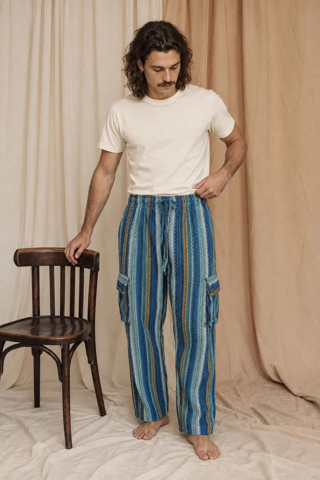 Riverstone Gheri Cargo Pants, blue and green gheri stripe, worn by a model beside a bentwood chair in the calico studio